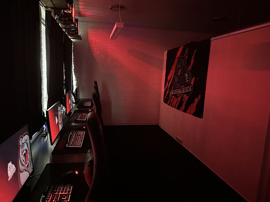 Det lille lokale i rødt lys med gaming-pladserne langs væggen og Espergærde Esport-banneret