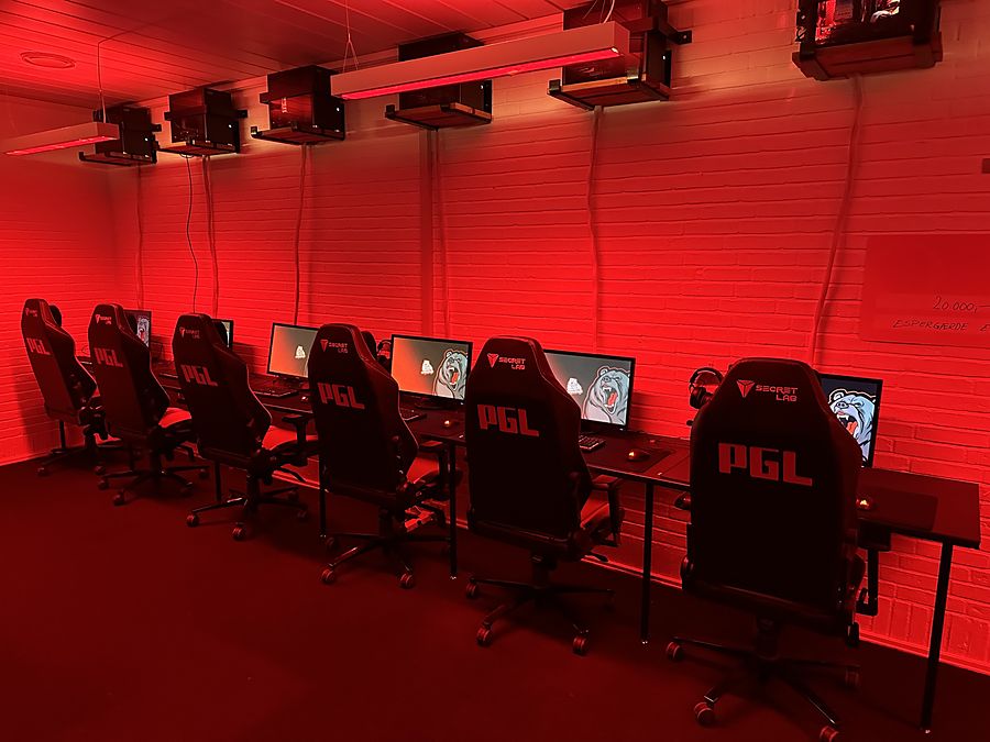Gamerstole og skærme på række i rødt lys i det store lokale